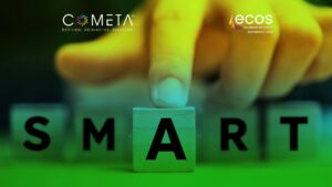 Primer plano de una mano colocando la letra "A" en la palabra SMART, formada con bloques de madera, que representa el concepto de objetivos estratégicos SMART en la planificación organizacional. El logotipo de COMETA aparece en la esquina superior izquierda y el logotipo de ECOS Resiliencia para la Sociedad Civil en la esquina superior derecha.